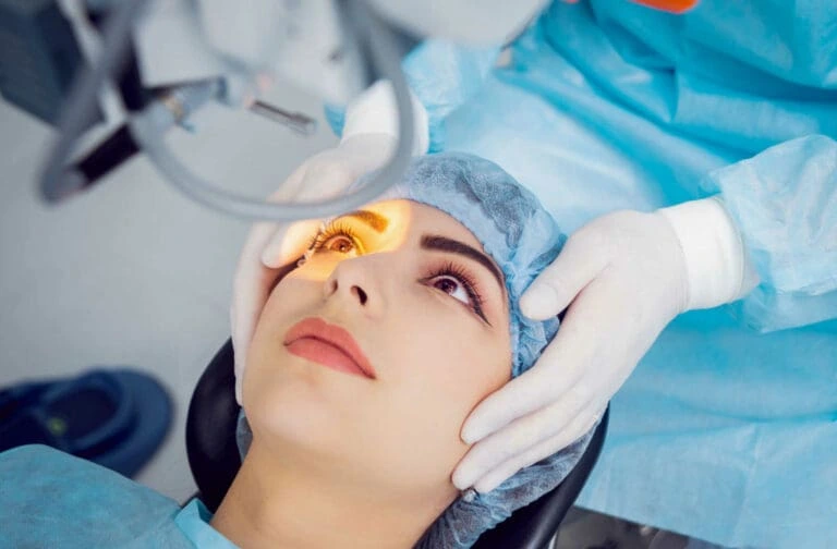 Close-up of a woman undergoing cataract surgery with a surgeon's hands guiding her eye.