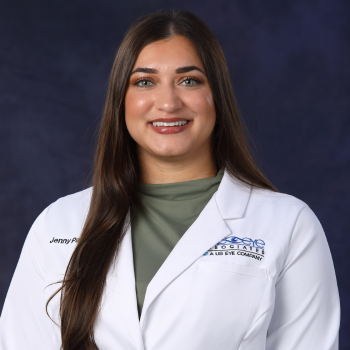 Portrait of a female healthcare professional in a white lab coat smiling at the camera against a dark blue background.